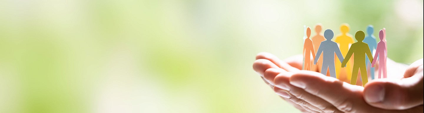 Hands supporting colorful paper people stock image