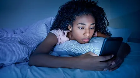 Teen girl texting in bed