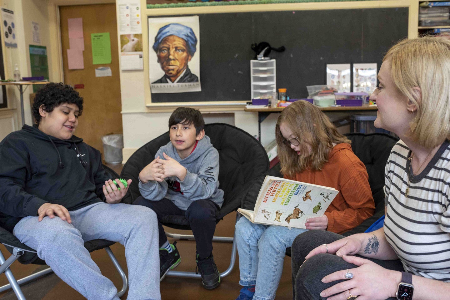 An educator talks with three students in a classroom