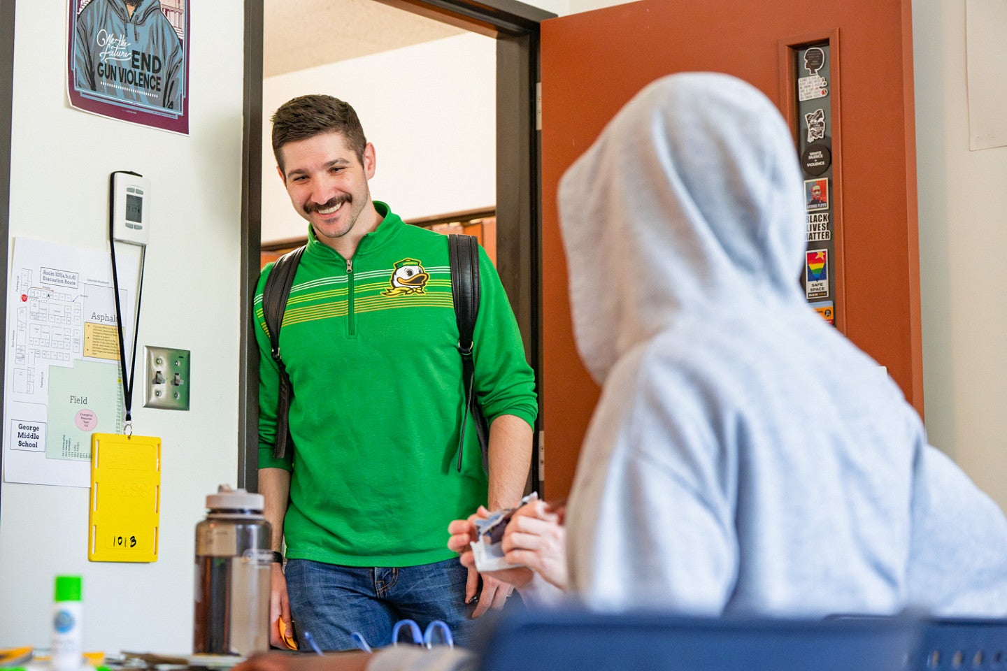 A student from the University of Oregon Ballmer Institute for Children's Behavioral Health studying to be a Behavioral Health and Wellness Practioner leans in a doorway while talking to a younger student