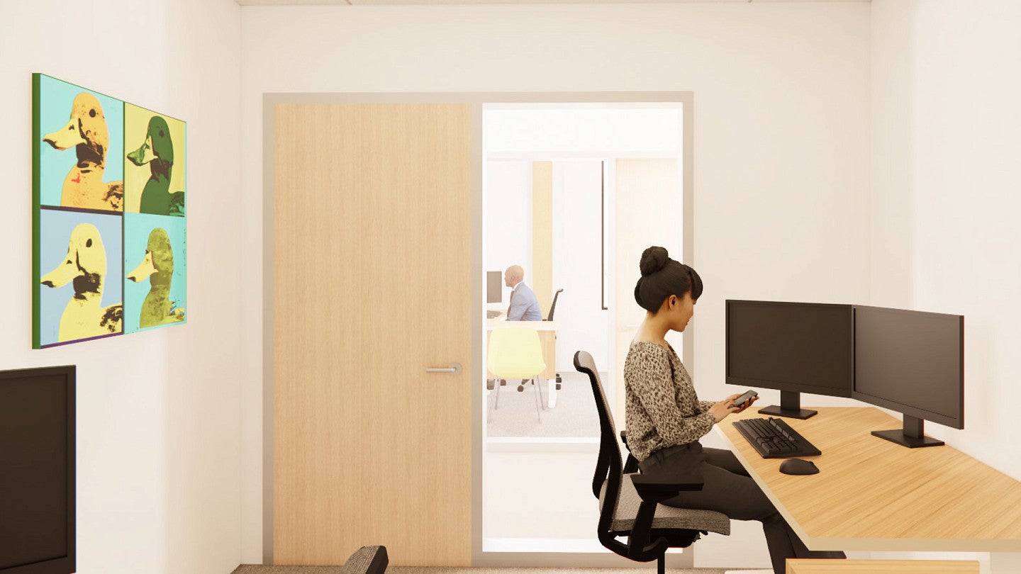 Architectural rendering of a telehealth office, with a woman working at a desktop with two monitors and a cell phone