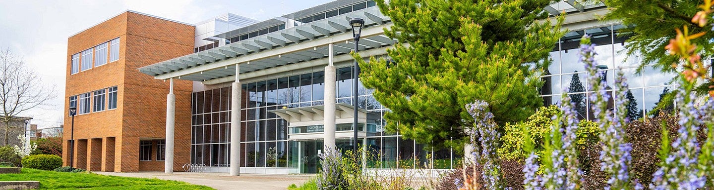University of Oregon Portland Library and Learning Center is shown in the background with flowers and vegetation in the foreground