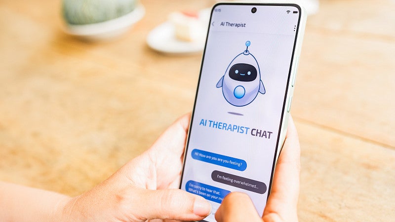 Person holding a smartphone displaying an AI therapist chat app.