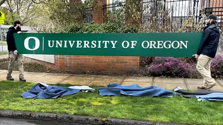 Two people holding a University of Oregon sign