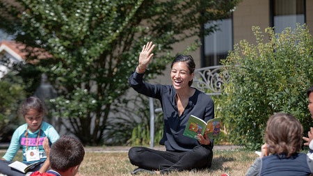 A teacher raises her hand to students