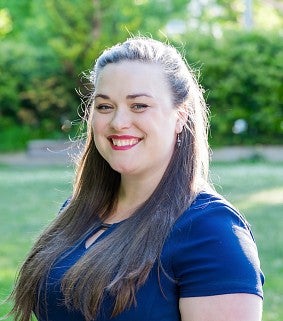 A woman in a blue dress smiles on a bright sunny day