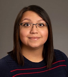 a woman in glasses smiles in an official portrait.