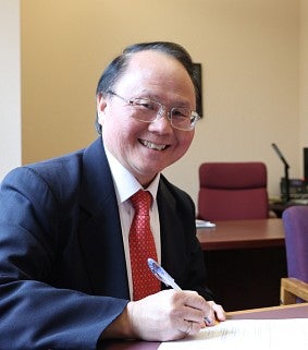 a man smiles while signing a document