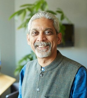 a man smiles for a portrait with a plant in the background