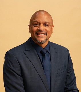portrait of a smiling man wearing a navy suit and tie