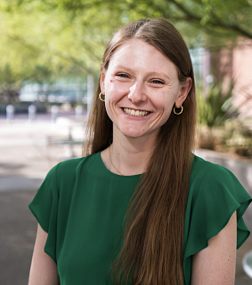Mary Kuckertz smiling outdoors, with long reddish-brown hair and a green top.