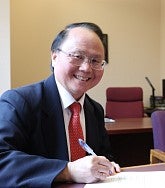 a man smiles while signing a document