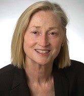 woman smiles for a portrait set against a white backdrop