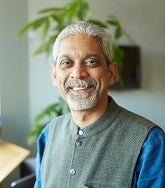 a man smiles for a portrait with a plant in the background